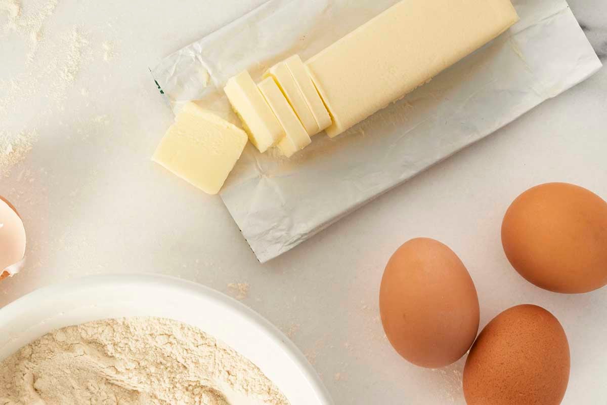 Sliced butter next to bowl of flour 