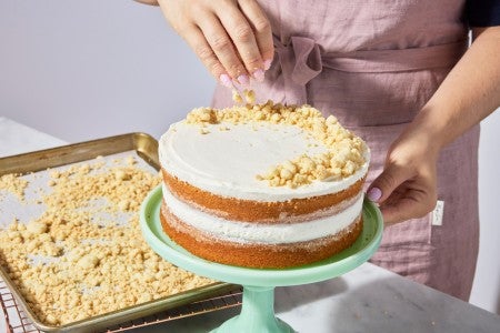 Cake crumbs being sprinkled on top of cake