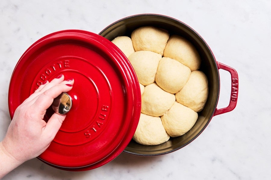 Proofed dinner rolls in cherry red Dutch oven