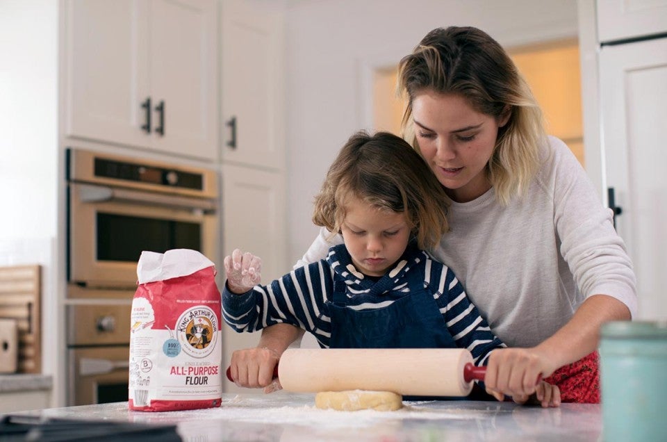 A mother and son using a rolling pin to roll out cookie dough