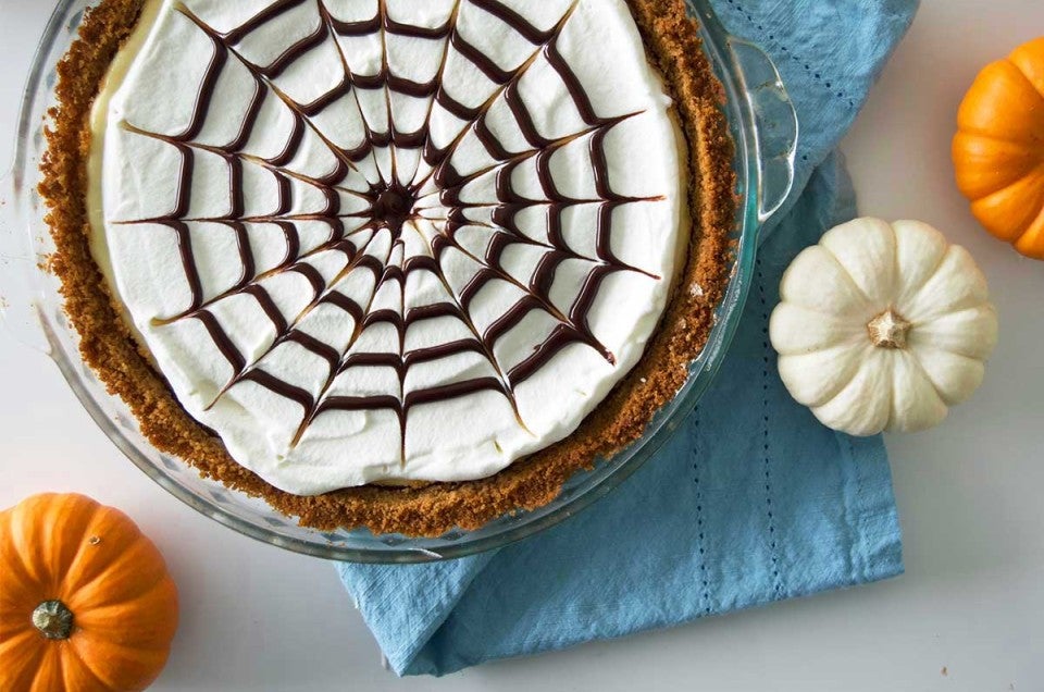 Spider web cheesecake surrounded by mini pumpkins