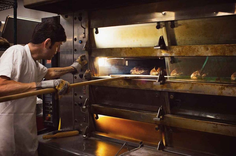 Baker putting loaves in oven