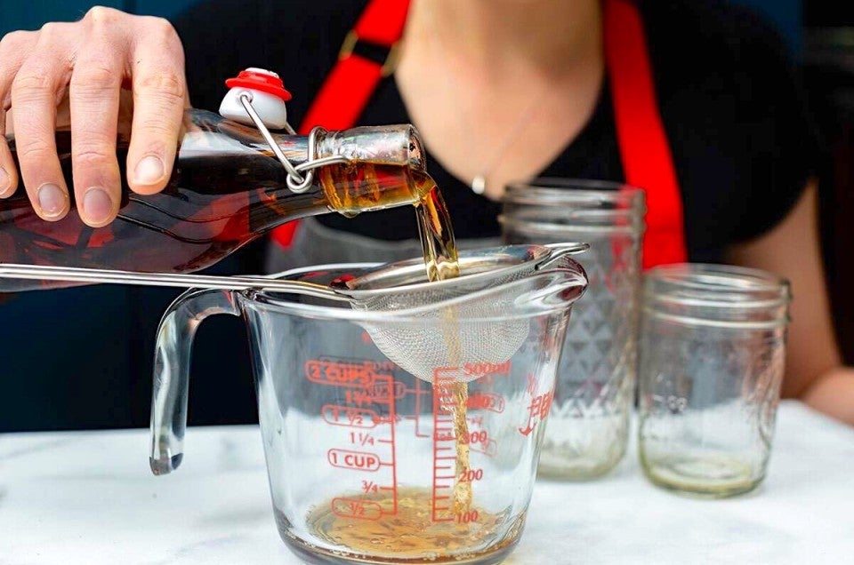 Straining homemade vanilla into a measuring cup.