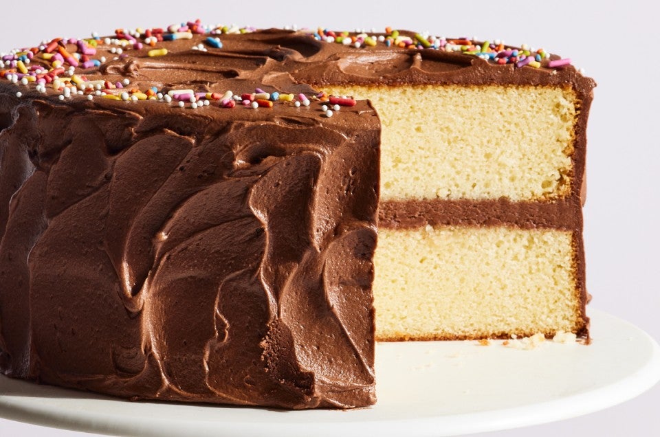 Chocolate frosted birthday cake with a slice cut out of it