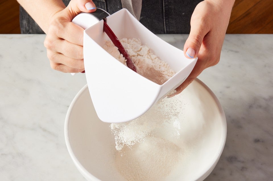 flour sifter being used over a bowl