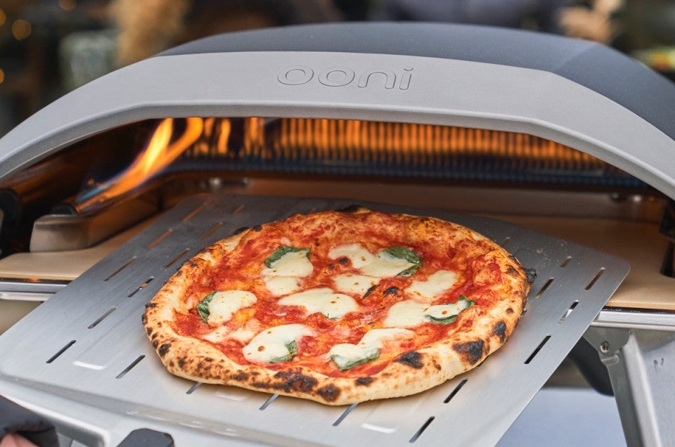 Pizza being pulled from Ooni pizza oven