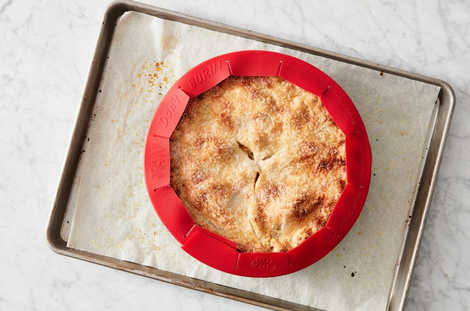 well baked pie on a sheet pan with a pie crust shield