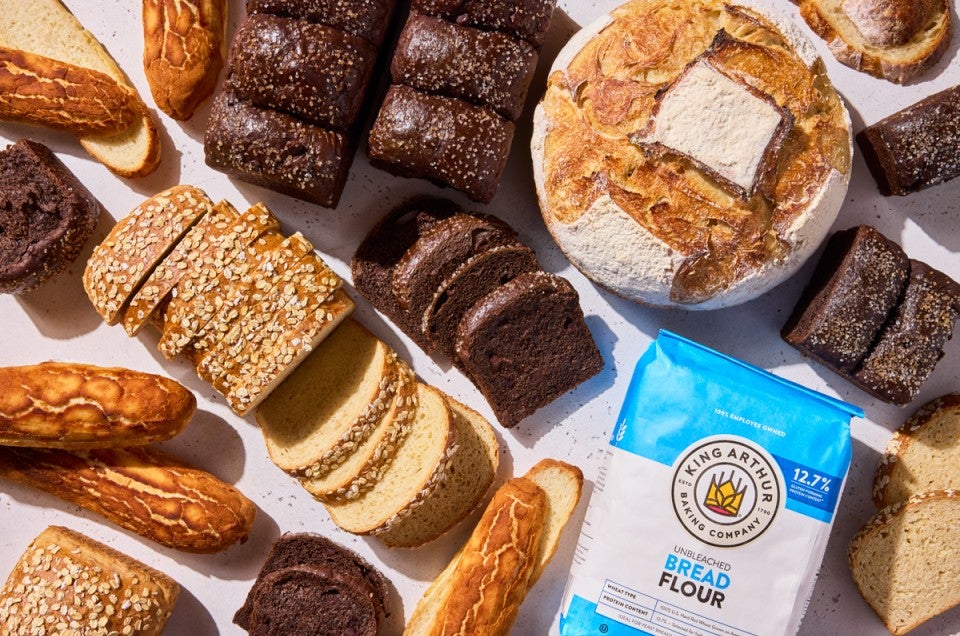 Multiple loaves of different breads next to a bag of bread flour