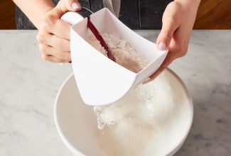 flour sifter being used over a bowl