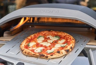 Pizza being pulled from Ooni pizza oven
