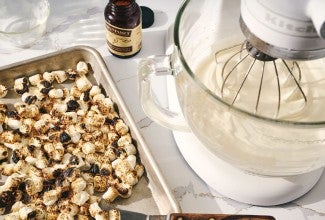 A baking sheet filled with roasted marshmallows next to a stand mixer bowl of whipped cream