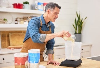 baker pouring sourdough starter into dough bucket