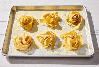 Nests of fresh pasta on a sheet pan