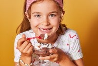 A little girl eating chocolate pudding