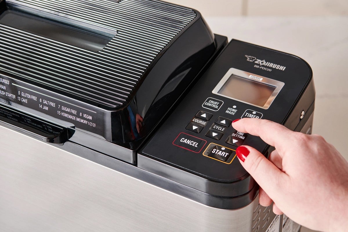 Baker pressing button on bread machine panel