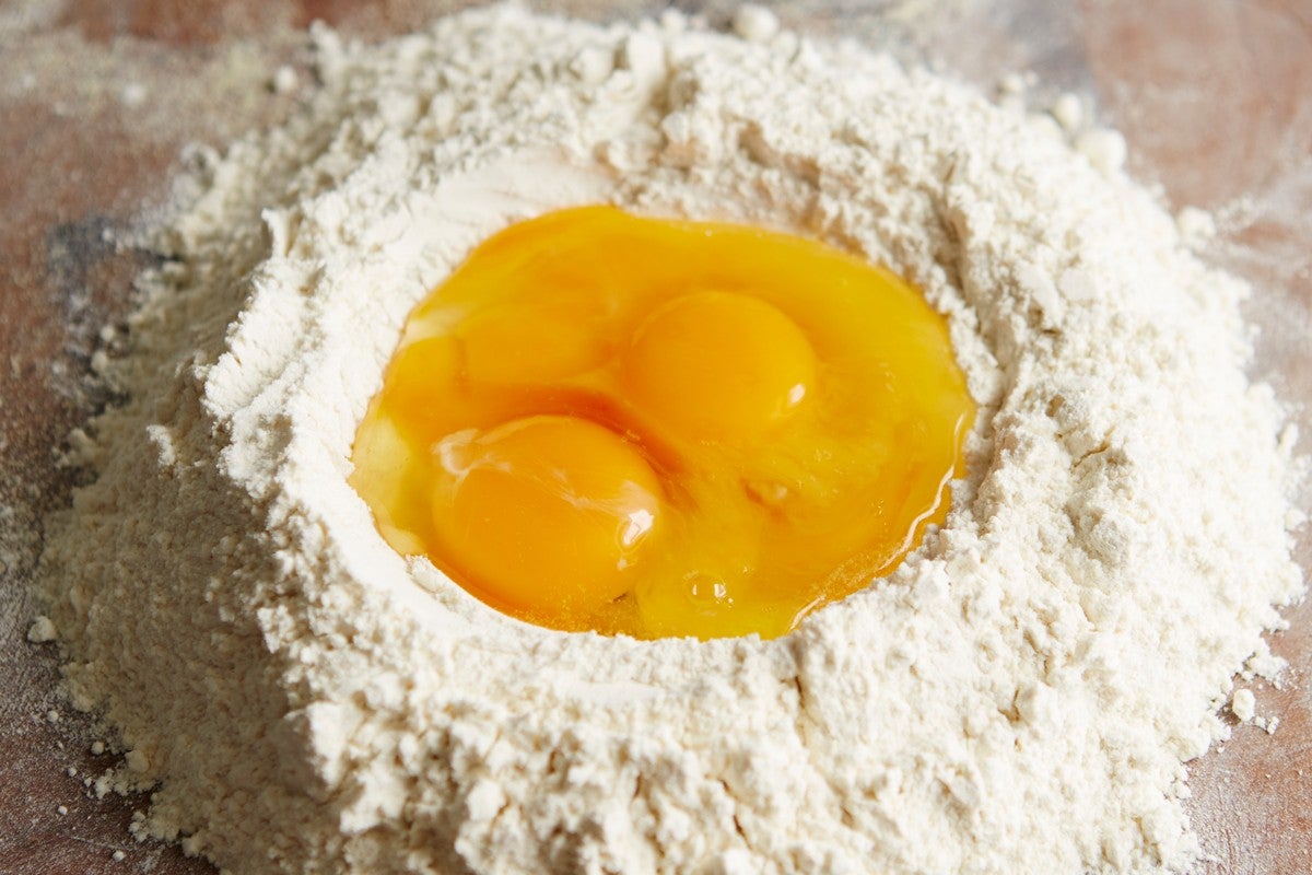 Eggs in a well of flour to make pasta dough