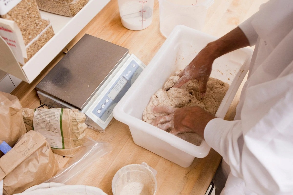 Baker using hands to mix whole grain bread dough