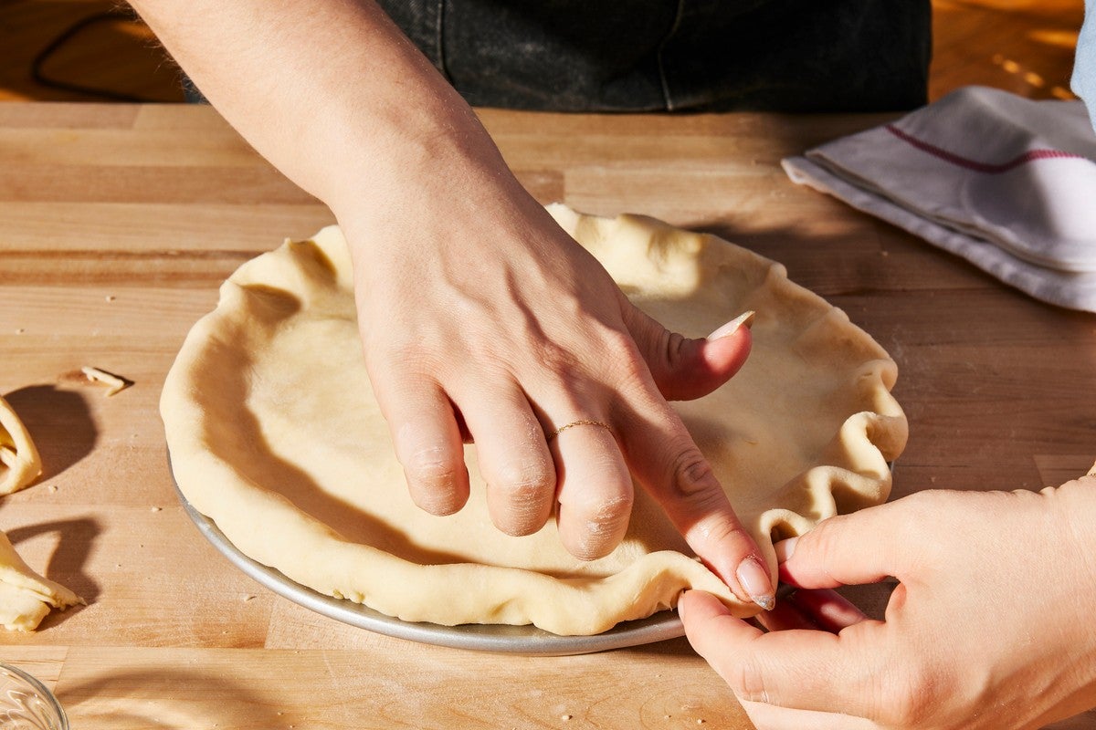 Hands crimping apple pie crust