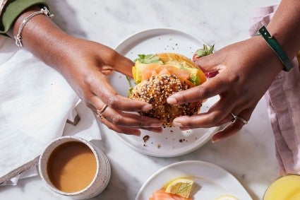 Hands holding filled Ultimate Sandwich Bagel