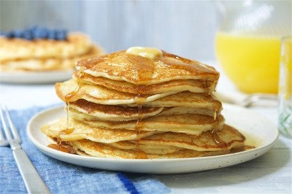 Stack of pancakes on a plate with melted butter dripping down. 
