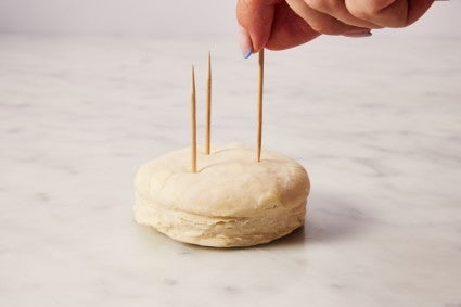 Placing three toothpicks in biscuit dough