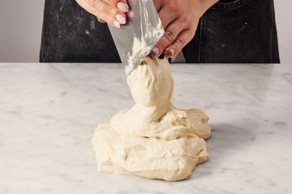 Cut the dough that is placed on top of the bread dough pile.