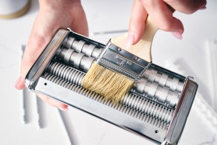 Using brush to clean parts of pasta maker