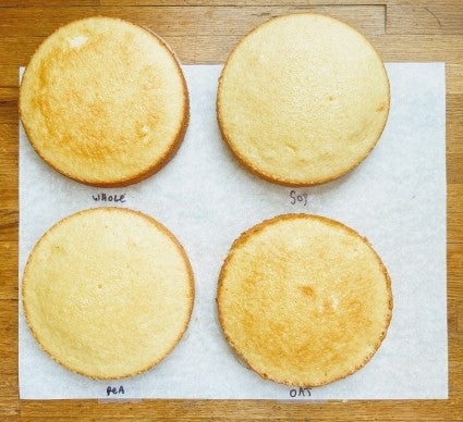 Top-down view of four round layers of hot milk cake baked with four different types of milk.