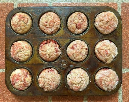 Top-down photo of strawberry muffins cooling in a muffin pan.