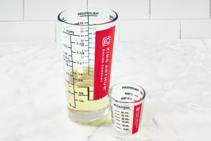 Liquid measuring cup and mini liquid measuring cup on marble surface