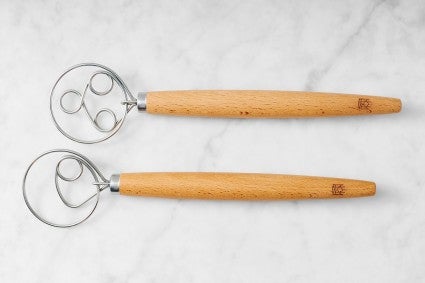 Dough whisk and batter whisk on marble surface