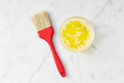 Pastry brush next to small bowl of melted butter