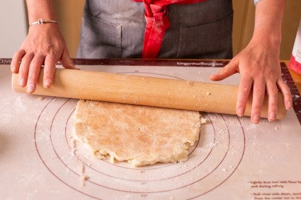 Straight rolling pin being used to roll out pie dough