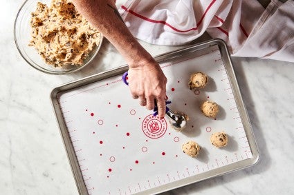 chocolate chip cookie dough being scooped onto a baking sheet