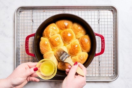 Brush the melted butter over the baked Dutch oven dinner rolls