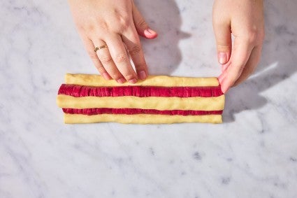 Attaching vanilla cookie dough to red heart cookie dough